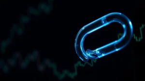 Close-up of a glowing blue Chainlink symbol against a dark financial chart background