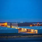 Bitcoin mining and data center buildings at dusk with power lines and substation